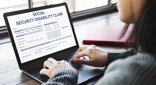 woman filling out social security distality claim form on laptop