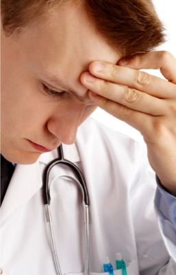 Doctor looking down with hand on forehead 