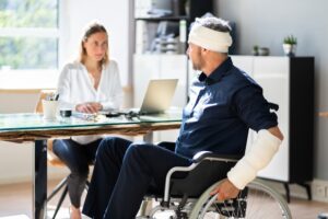 A man with injuries in a wheelchair asks a woman how can a lawyer help with SSDI denial