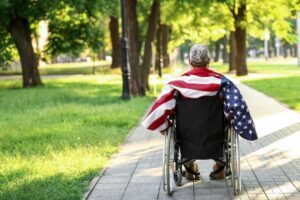 Young veteran in a wheelchair with USA flag on his way to apply for VA disability benefits. Veterans Disability Claims Process – What’s Determined in a VA Disability Decision
