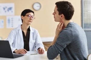 A man touching his neck while consulting a doctor. Learn about whether you can get disability benefits for chloracne.