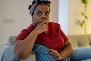 A woman sitting on her couch, wondering if POTS qualifies as a Long Term Disability.