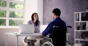 Man in a wheelchair who is dealing with a disability speaking to an attorney about how to appeal a Long Term Disability claim denial in Lafayette