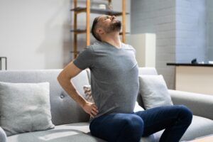 A man holds his back in pain and wonders if sciatica is a disability.