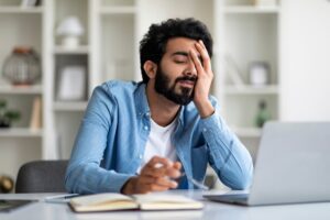 An exhausted man trying to work on a computer wonders if you can get disability benefits for hypersomnolence disorder.