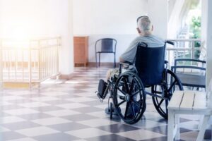 Person in a wheelchair sitting alone on a porch, representing a claimant denied disability benefits by The Hartford