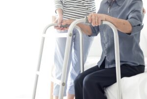 Caregiver helping a person use a walker, representing a claimant receiving care while appealing a denial from The Standard