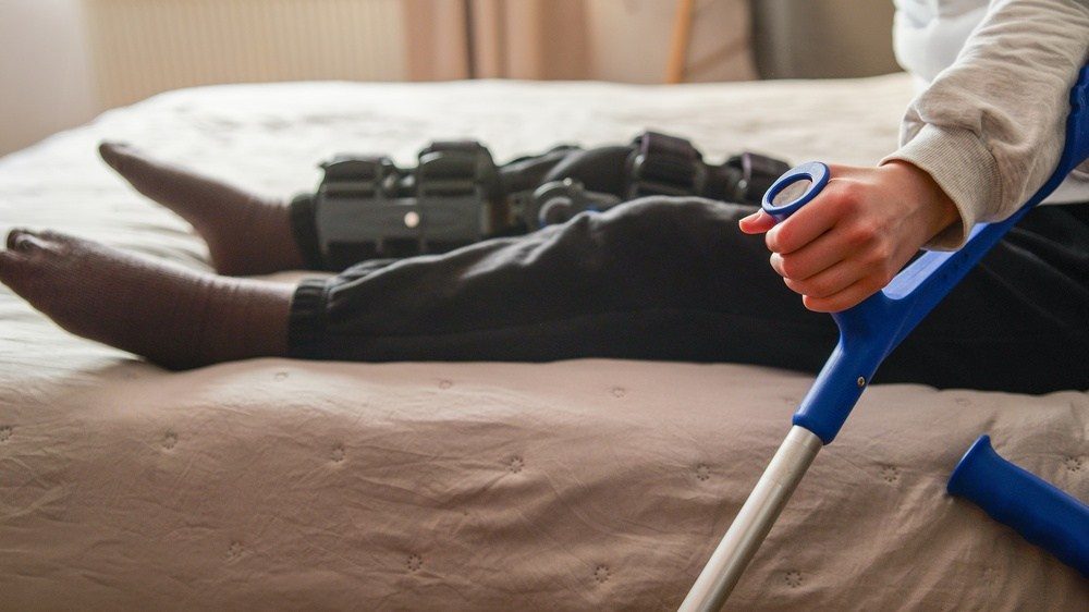 Close-up of leg braces and a forearm crutch used by someone with a lifelong disability