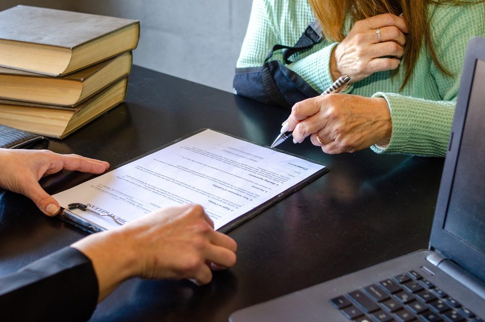 Abogado revisando una carta de denegación con un cliente, representando una apelación tras una denegación en reconsideración