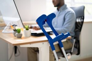 Crutches beside a desk where someone is working, representing a Social Security disability reconsideration denial